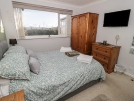 A bedroom with a bed a wooden wardrobe a wooden dresser and a wall-mounted TV at Chy Bean in Abergele