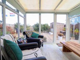 A conservatory with armchairs and a coffee table at Chy Bean Abergele