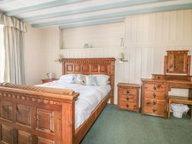 A bedroom with a wooden bed and nightstand at Dovecote in Gorran Haven