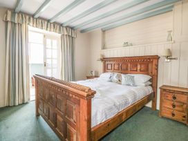 A bedroom with a wooden bed and nightstand at Dovecote in Gorran Haven