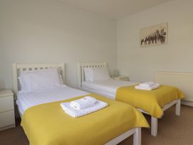 A bedroom with two beds and a painting at Treverrion in Gorran Haven
