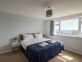 A bedroom with a bed and view of the sea at Treverrion in Gorran Haven