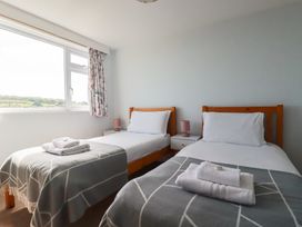 A bedroom with two single beds and a window at Treverrion in Gorran Haven