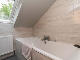 A bathroom with a bathtub and window at Fortunatus in Whitby