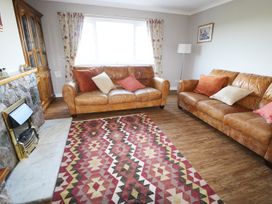 A living room with two leather sofas a patterned rug and a fireplace at Pen Y Cae in Llansannan