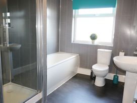 A bathroom with a shower, bathtub, toilet, and sink with a window and a potted plant at Pen Y Cae in Llansannan