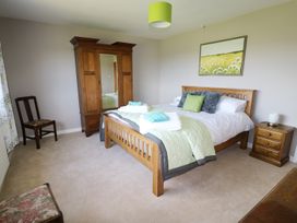 A bedroom with a wooden bed with linens and towels a wooden wardrobe a wooden chair a nightstand with a lamp and a painting on the wall at Pen Y Cae in Llansannan