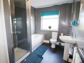 A bathroom with a shower enclosure bathtub toilet sink mats and window at Pen Y Cae in Llansannan