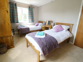 A bedroom with two single beds with purple throws and wooden furniture at Pen Y Cae in Llansannan