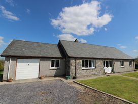 A single-story house with a stone and pebble dash exterior under a blue sky at Pen Y Cae in Llansannan