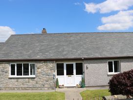 The front view of a stone and pebble dash house with a white door and two windows at Pen Y Cae in Llansannan