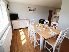 A dining room with a wooden table and six chairs set with tea cups and plates at Pen Y Cae in Llansannan