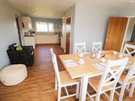 A kitchen and dining area with a wooden dining table set for tea and a black leather armchair at Pen Y Cae in Llansannan