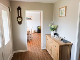 A hallway with a wooden sideboard holding flowers and a decorative sign with a door leading to a dining area at Pen Y Cae in Llansannan