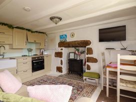 A kitchen with cabinets and a fireplace at Longview Cottage in Penwithick neat St Austell