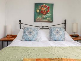 A bedroom with a bed and floral wall art at Longview Cottage in Penwithick neat St Austell