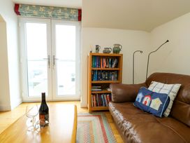 A living room with a bookshelf and a sofa at Maelog, 14 Tides Reach Rhosneigr