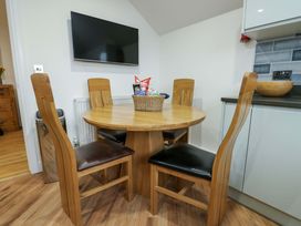 A dining room with a round wooden table and chairs at Maelog, 14 Tides Reach, Rhosneigr