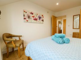 A bedroom with a bed and chair at Maelog, 14 Tides Reach Rhosneigr