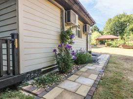 A side view of a house with flower plants along a paved walkway and a garden area with a gazebo at Badger View in Culverstone Green near Chatham