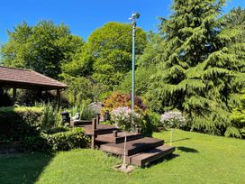 A garden area with wooden steps a lamp post trees and a covered seating area at Badger View in Culverstone Green near Chatham