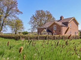 A brick house with a wooden fence and tall grass in the foreground at Foremans House in Bridlington