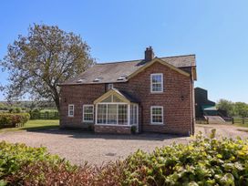 A brick house with a gravel driveway and a large tree in a rural setting at Foremans House in Bridlington