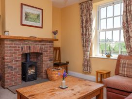 A living room with a brick fireplace a wooden coffee table a window with floral curtains and a cushioned chair at Foremans House in Bridlington