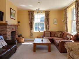 A living room with leather sofas a wooden coffee table a brick fireplace and floral curtains at Foremans House in Bridlington