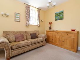 A sitting room with a patterned sofa two cushions a wooden sideboard with decorations and curtains at Foremans House in Bridlington