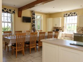 A kitchen and dining area with a long dining table set with chairs and tableware at Foremans House in Bridlington