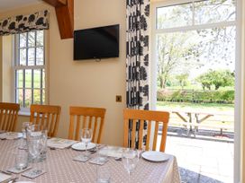 A dining area with a table set with plates glasses and cutlery by windows and a door opening to an outdoor patio at Foremans House in Bridlington