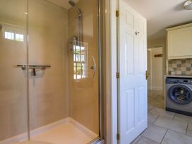 A bathroom with a glass shower enclosure next to a door leading to a laundry room with a washing machine at Foremans House in Bridlington