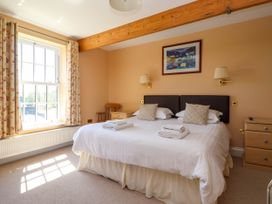 A bedroom with a double bed with white linens two bedside tables a wooden chair and a large window at Foremans House in Bridlington