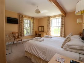 A bedroom with a double bed two windows with curtains a wooden chair a desk a mounted television and folded towels on the bed at Foremans House in Bridlington