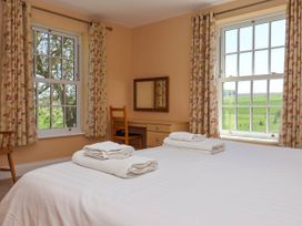 A bedroom with a bed and folded towels near windows with patterned curtains at Foremans House Bridlington