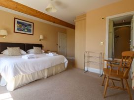 A bedroom with a double bed, pillows, folded towels, a wooden chair, a framed picture, and an en suite bathroom at Foremans House in Bridlington
