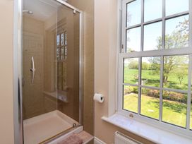 A bathroom with a glass shower enclosure a window showing a green lawn and trees at Foremans House in Bridlington