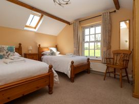 A bedroom with two single wooden beds a wooden chair a bedside table a window with curtains and a skylight at Foreman's House in Bridlington