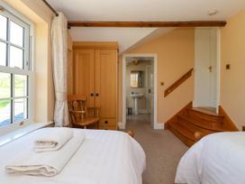 A bedroom with two beds a wooden chair a wardrobe and a doorway leading to a bathroom at Foremans House in Bridlington