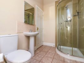 A bathroom with a toilet sink mirror and curved glass shower enclosure at Foremans House in Bridlington
