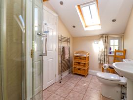 A bathroom with a glass shower door a white door a towel rack a wicker storage unit a small window with curtains a toilet a pedestal sink and a wooden chair at Foremans House in Bridlington