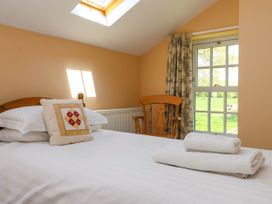 A bedroom with a bed, pillows, folded towels, a wooden chair, window with curtains and a skylight at Foreman's House in Bridlington