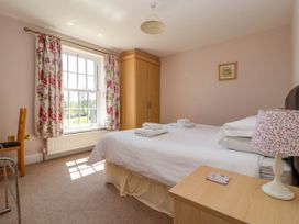 A bedroom with a bed and floral curtains next to a window at Foremans House in Bridlington