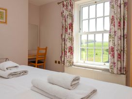 A bedroom with a bed with folded towels a wooden chair a window with floral curtains and a view of fields at Foremans House Bridlington