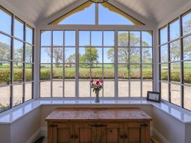 A window seating area with a wooden cabinet and flowers on the windowsill at Foremans House in Bridlington