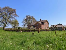 A brick house with a fenced yard and a small shed in a grassy field at Foremans House in Bridlington
