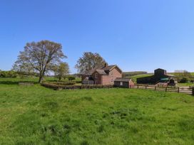 A brick house with fenced yard next to large tree and barn in a grassy field at Foremans House in Bridlington
