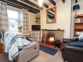 A living room with a fireplace and sofa at Merlin in Llithfaen near Nefyn