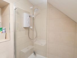 A shower with glass enclosure and tiled walls at Merlin in Llithfaen near Nefyn